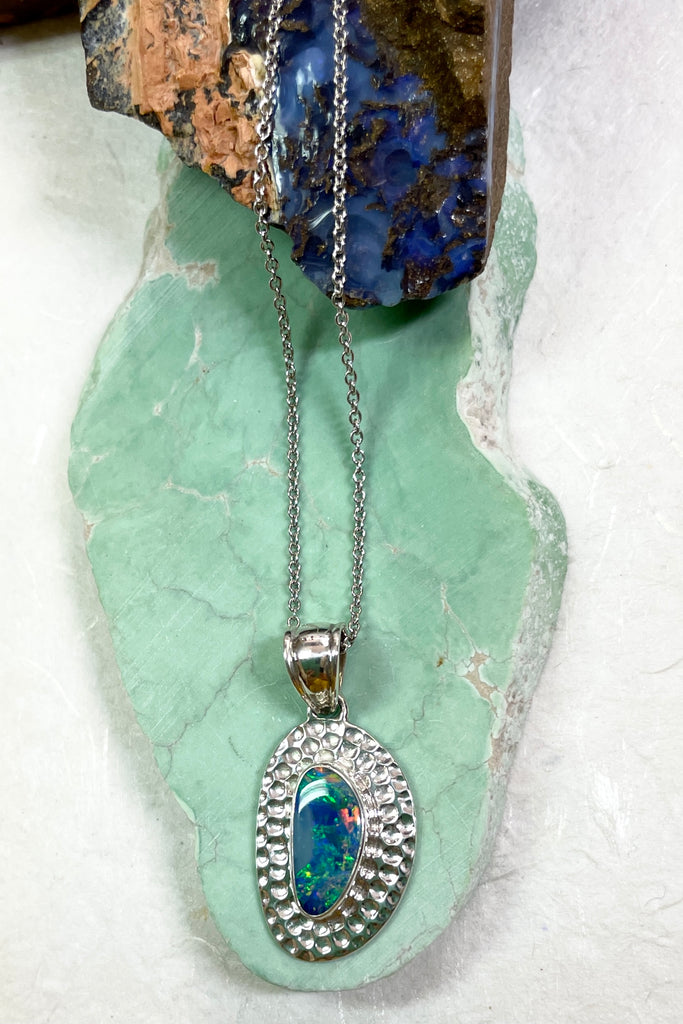 The Australian opal pendant is shaped into an abstract shape with a polished frame