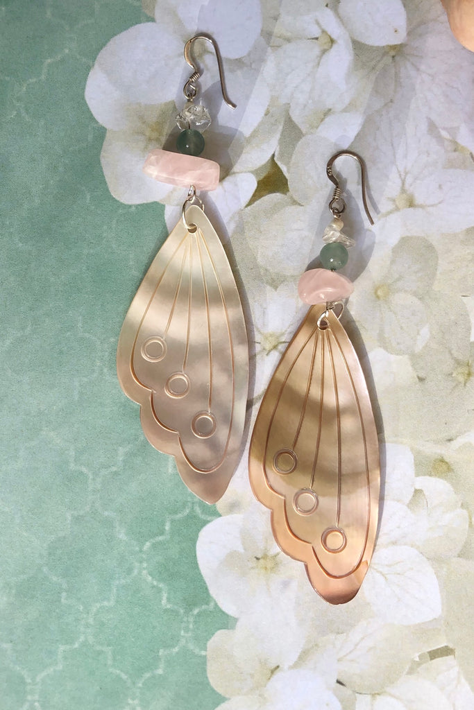 Serendipity Earrings Butterfly Wing Shell Pink are handmade exclusively for us. The gorgeous pale pink Mother of Pearl wing has been hand cut and polished. At the top there is a pebble of natural Rose Quartz, an Amazonite bead and a rock crystal bead.