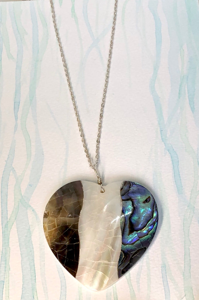 A charming heart shaped pendant, the surface is silvery grey blue and pearly white mother of pearl shell that has been applied to a base of shell, so it is lovey worn both ways around.