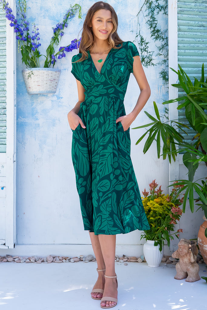 The Lizzie Botany Green Midi Dress is a gorgeous dark green based midi dress with a deep green botanical leaf print. The dress features cap sleeves, a deep v neckline, fitted basque waist with gathered bust, elastic shirring at back waist, side pockets and is made from woven 100% rayon.