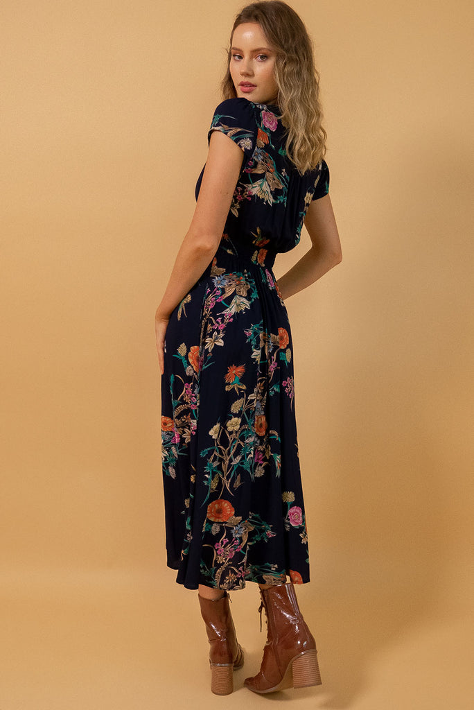 Lizzie Navy Bouquet Midi Dress features fitted elasticated waist, a cap sleeve and deep v neck and it comes in a dark navy with multicoloured floral design on a soft woven 100% rayon, perfect for vintage style lover.