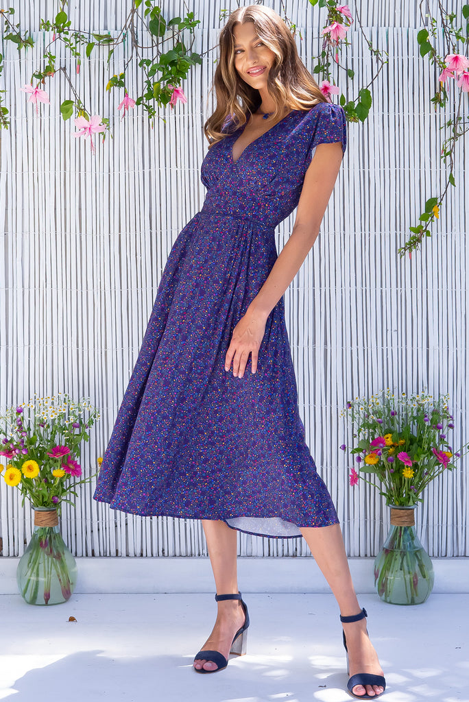The Lizzie Seashells Navy Midi Dress is a gorgeous navy based midi dress with a multicoloured ditzy seashell print. The dress features cap sleeves, a deep v neckline, fitted basque waist with gathered bust, elastic shirring at back waist, side pockets and is made from woven 100% rayon.
