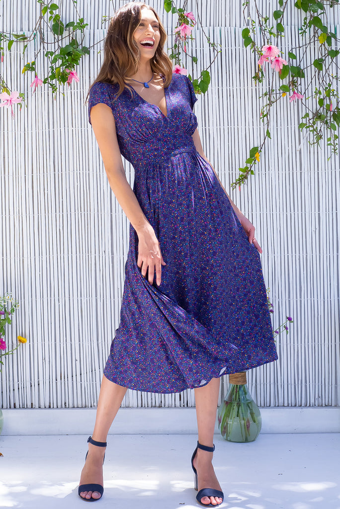 The Lizzie Seashells Navy Midi Dress is a gorgeous navy based midi dress with a multicoloured ditzy seashell print. The dress features cap sleeves, a deep v neckline, fitted basque waist with gathered bust, elastic shirring at back waist, side pockets and is made from woven 100% rayon.