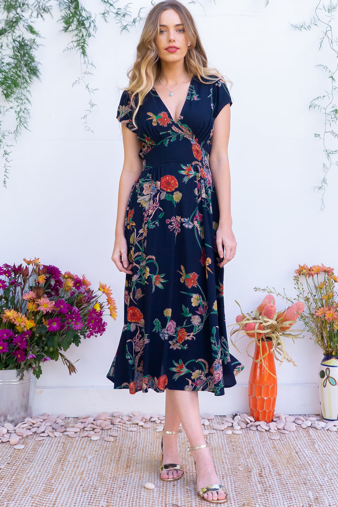 Lizzie Navy Bouquet Midi Dress features fitted elasticated waist, a cap sleeve and deep v neck and it comes in a dark navy with multicoloured floral design on a soft woven 100% rayon, perfect for vintage style lover.