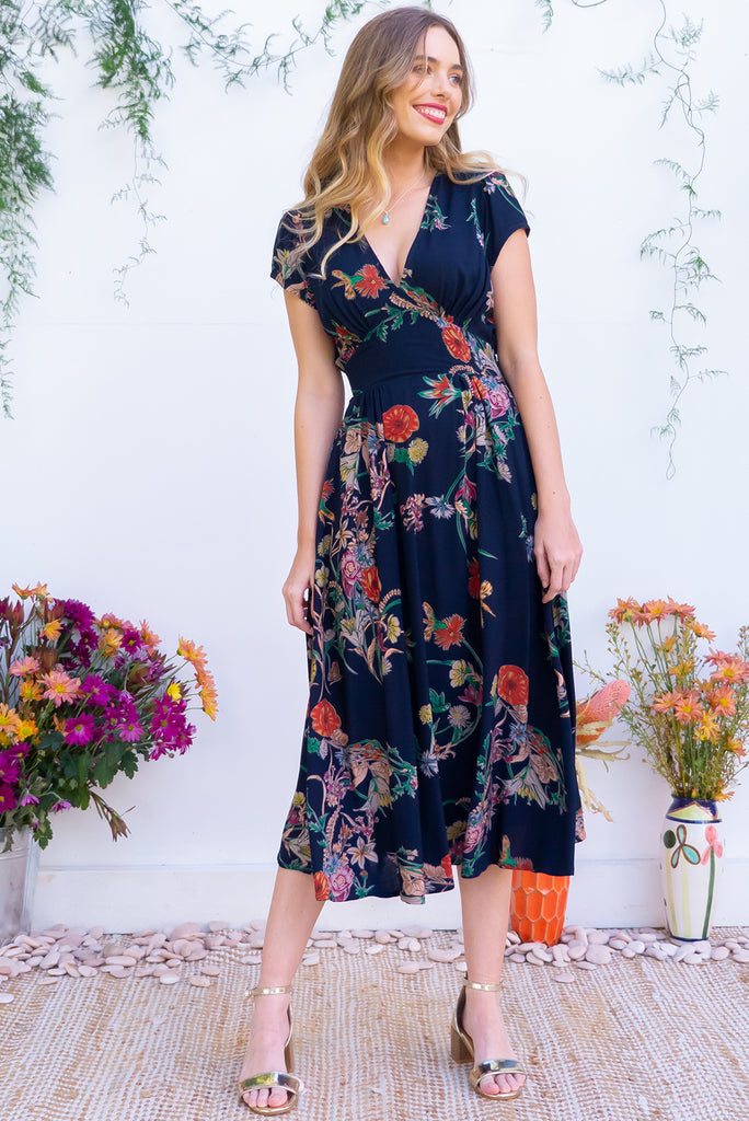 Lizzie Navy Bouquet Midi Dress features fitted elasticated waist, a cap sleeve and deep v neck and it comes in a dark navy with multicoloured floral design on a soft woven 100% rayon, perfect for vintage style lover.