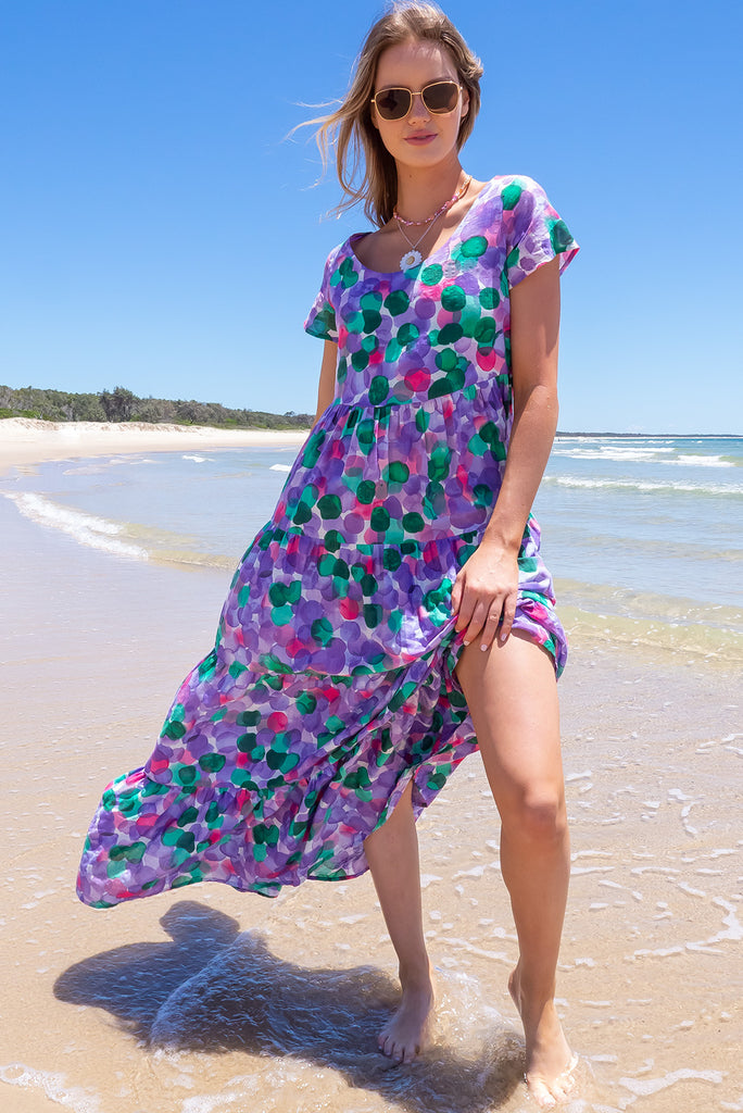 Our Lucky Lulu Is A Maxi Length Dress Featuring A Scooped Neckline, Adjustable Waist Tabs, Side Pockets And A Wide Tiered Skirt. The Bubbles Print Is A White Base With Purple, Green And Pink Wash Effect Bubbles All Over. Made From 100% Cotton.