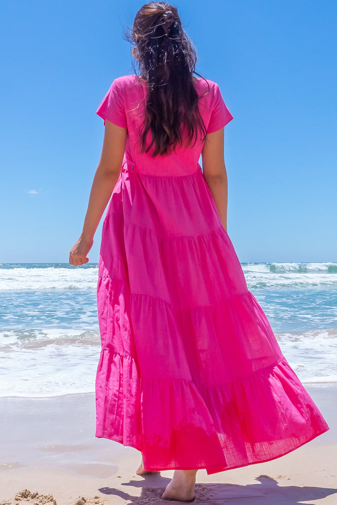 The Lucky Lulu Candy Tiered Maxi Dress is a stunning hot pink maxi dress. This dress features a scooped neckline, adjustable waist tabs, side pockets and a wide tiered skirt. Made from woven 100% cotton.