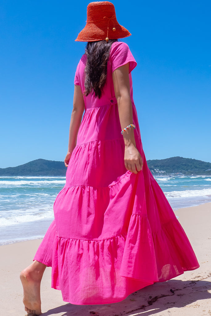 The Lucky Lulu Candy Tiered Maxi Dress is a stunning hot pink maxi dress. This dress features a scooped neckline, adjustable waist tabs, side pockets and a wide tiered skirt. Made from woven 100% cotton.