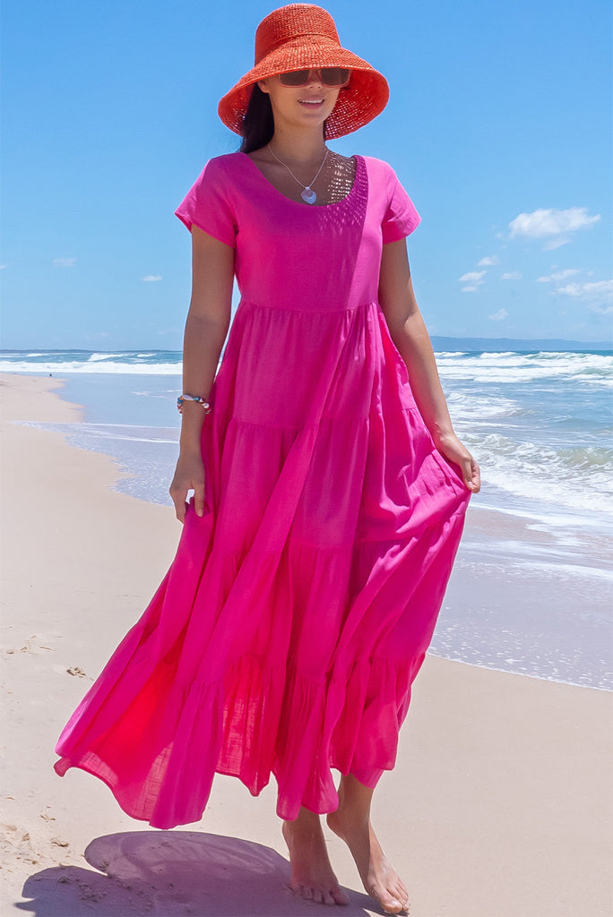 The Lucky Lulu Candy Tiered Maxi Dress is a stunning hot pink maxi dress. This dress features a scooped neckline, adjustable waist tabs, side pockets and a wide tiered skirt. Made from woven 100% cotton.