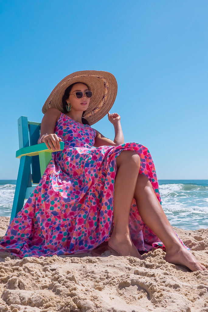 The Lulu Darling Sea Shells Pink Tiered Maxi Dress features a high neck with thin straps, high cut under arms, full tiered skirting from the bust down and deep side pockets. The pink based dress has a multicoloured seashell print all over in. Made from 100% cotton poplin.