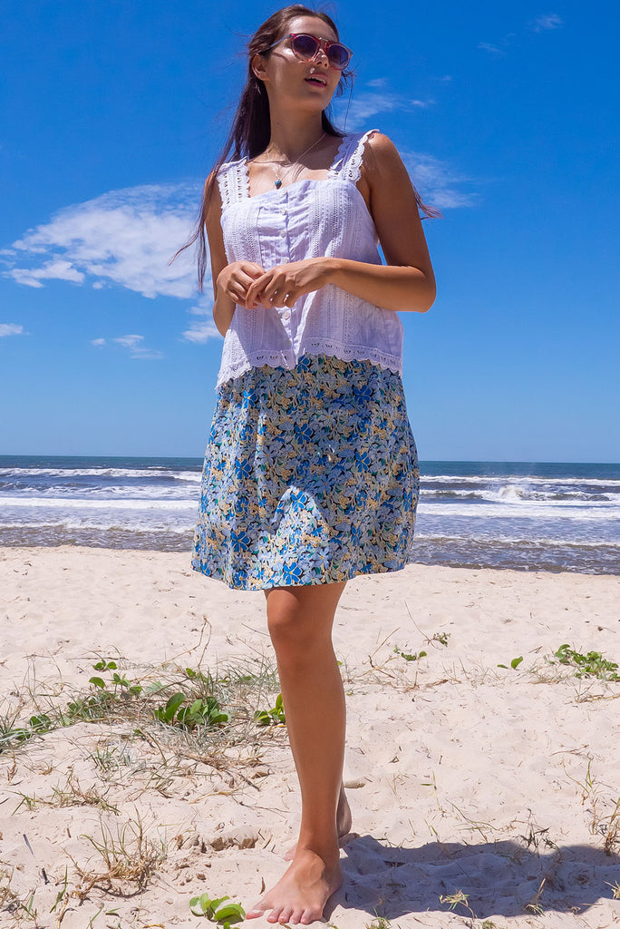 The Minnie Blue Note Mini Skirt is a beautiful teal mini skirt with a black base and blue floral print. The skirt is a comfortable slip-on style, a-line cut and features side pockets and an elasticated paper bag waistband. This mini skirt is woven 100% cotton.