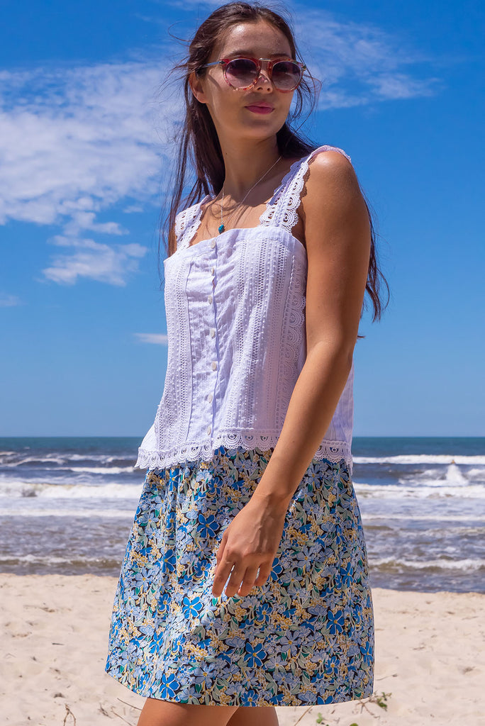 The Minnie Blue Note Mini Skirt is a beautiful teal mini skirt with a black base and blue floral print. The skirt is a comfortable slip-on style, a-line cut and features side pockets and an elasticated paper bag waistband. This mini skirt is woven 100% cotton.