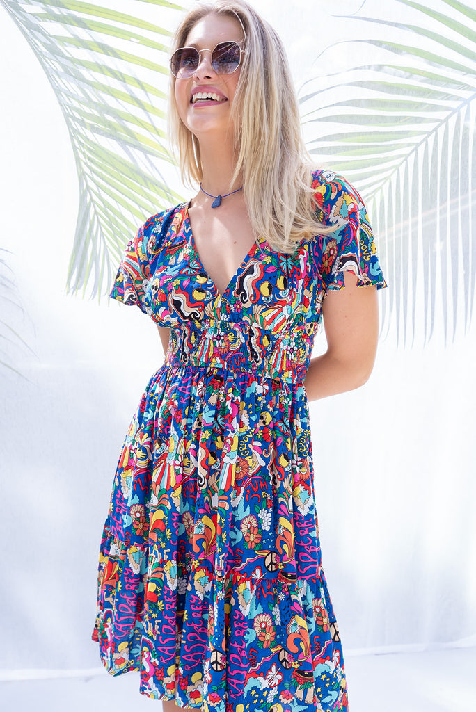 The Mirabella 60s Print Dress is a bold deep blue based mini dress with a vibrant multicoloured pop art retro print. The mini dress features a lined bust, v neckline, drop flutter sleeves, low v back with tie at the top, cinched elastic waist, tiered skirt and side pockets. This dress is made from woven 100% rayon.