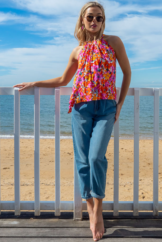 Our Nuance Top Features A High Neck With Gathering, Adjustable Neckline, Tie Back Keyhole, Shortened Front And An Airy Cut. The Viva L'Orange Print Is A Red Base With A Bright Pink, Orange, White And Green Botanical Print. 100% Rayon.