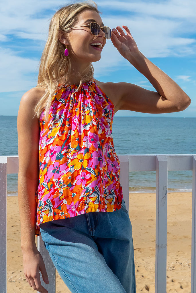 Our Nuance Top Features A High Neck With Gathering, Adjustable Neckline, Tie Back Keyhole, Shortened Front And An Airy Cut. The Viva L'Orange Print Is A Red Base With A Bright Pink, Orange, White And Green Botanical Print. 100% Rayon.