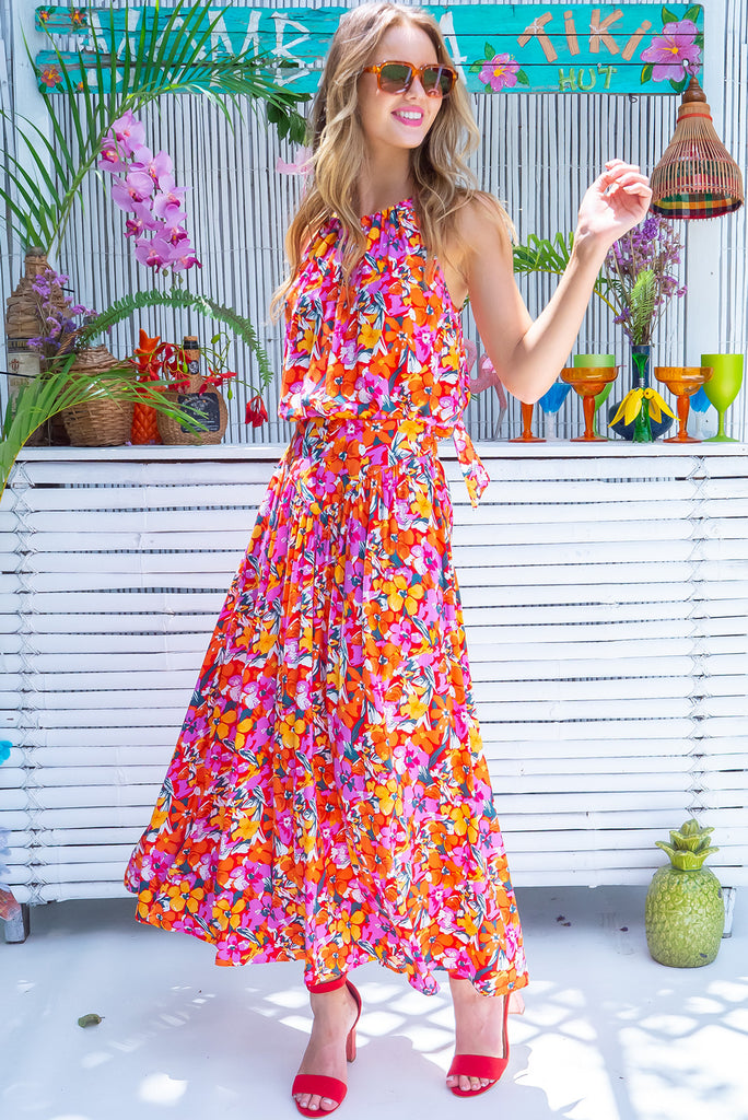 Our Nuance Top Features A High Neck With Gathering, Adjustable Neckline, Tie Back Keyhole, Shortened Front And An Airy Cut. The Viva L'Orange Print Is A Red Base With A Bright Pink, Orange, White And Green Botanical Print. 100% Rayon.