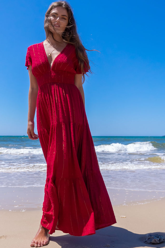 The Romance Dark Red Maxi Dress is a stunning rich red tone maxi dress with textured spots and lurex stripes. The dress features a lined bust, deep plunge v neckline, drop flutter sleeves, low v back with tie at the top, cinched elastic was it, full tiered skirt and side pockets. This dress is made from woven 100% crinkle viscose. 
