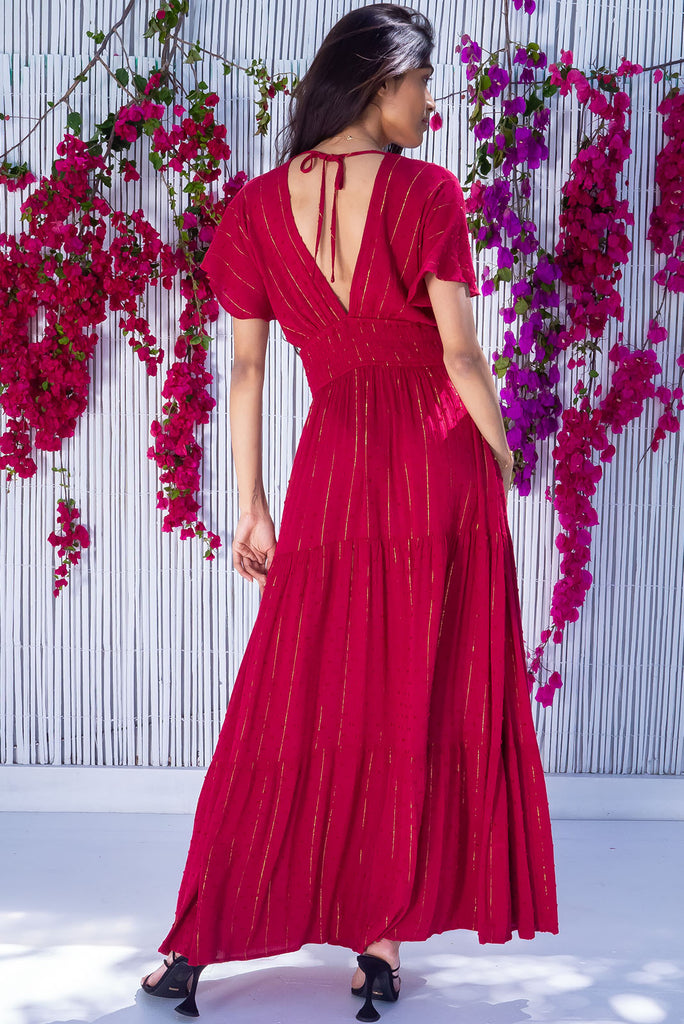 The Romance Dark Red Maxi Dress is a stunning rich red tone maxi dress with textured spots and lurex stripes. The dress features a lined bust, deep plunge v neckline, drop flutter sleeves, low v back with tie at the top, cinched elastic was it, full tiered skirt and side pockets. This dress is made from woven 100% crinkle viscose. 