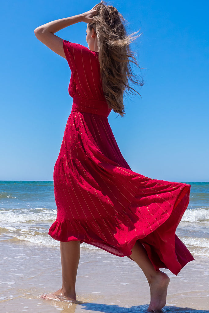 The Romance Dark Red Maxi Dress is a stunning rich red tone maxi dress with textured spots and lurex stripes. The dress features a lined bust, deep plunge v neckline, drop flutter sleeves, low v back with tie at the top, cinched elastic was it, full tiered skirt and side pockets. This dress is made from woven 100% crinkle viscose. 