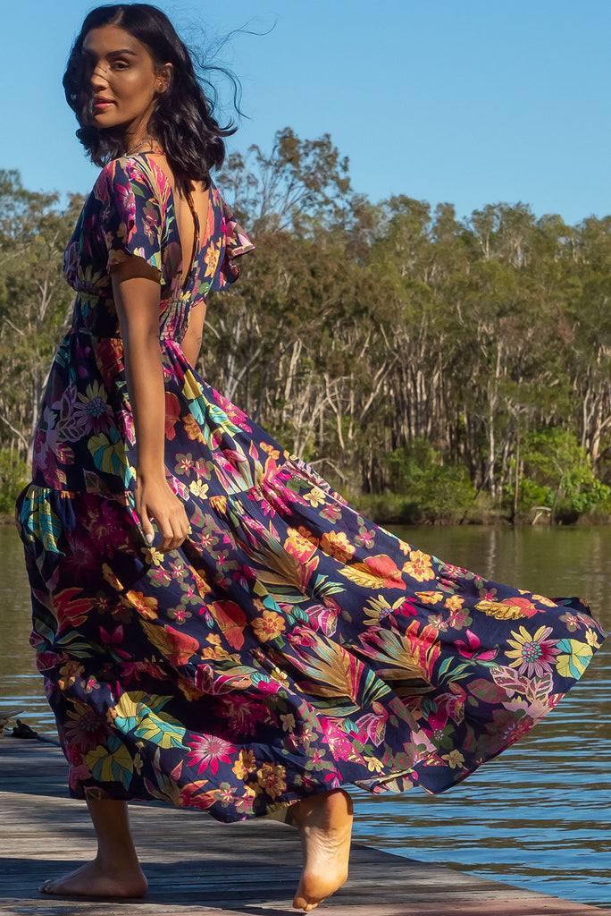 The Romance Jungle Brights Maxi Dress is a stunning 100% cotton, navy based maxi dress with a bright botanical print. The dress features a deep plunge V neckline, lined bust, drop flutter sleeves, elasticated waist, side pockets and a low V back with tie at the top.