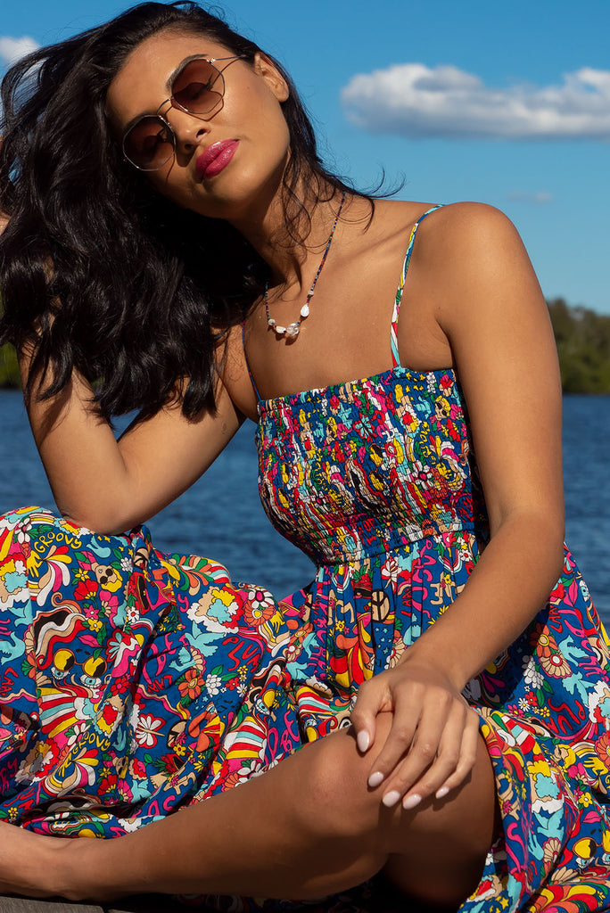 The Stardust Peace and Love Maxi Dress is a bold deep blue based dress with a vibrant multicoloured pop art retro print. This maxi dress features an elasticated shirred bodice, textured cheesecloth fabric, adjustable thin straps, tiered skirt and side pockets. Made from a woven cotton/rayon blend.