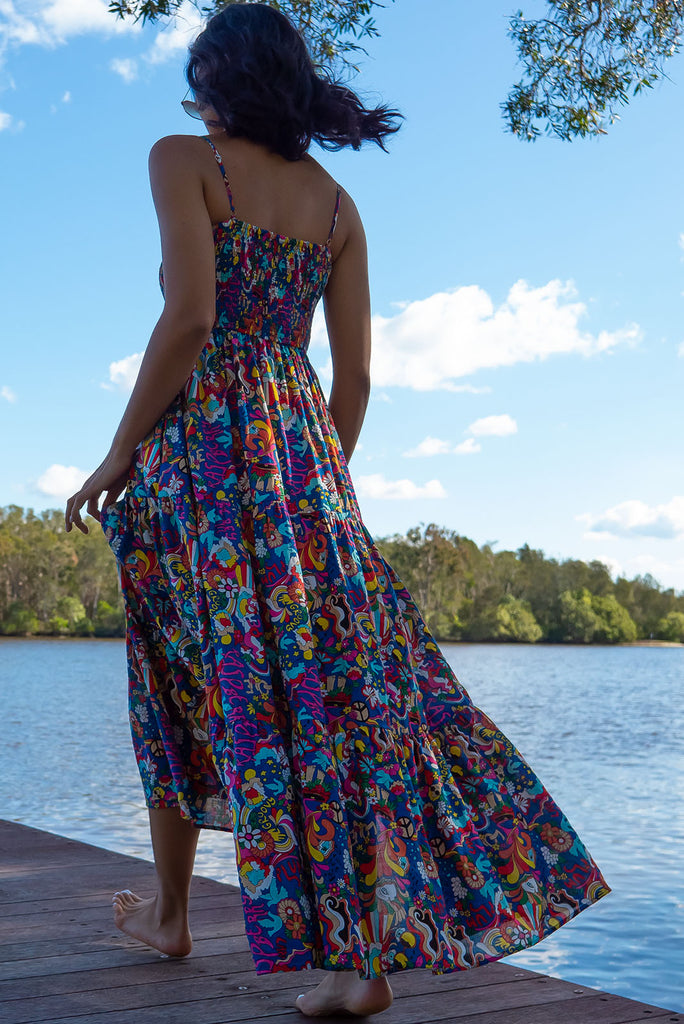 The Stardust Peace and Love Maxi Dress is a bold deep blue based dress with a vibrant multicoloured pop art retro print. This maxi dress features an elasticated shirred bodice, textured cheesecloth fabric, adjustable thin straps, tiered skirt and side pockets. Made from a woven cotton/rayon blend.