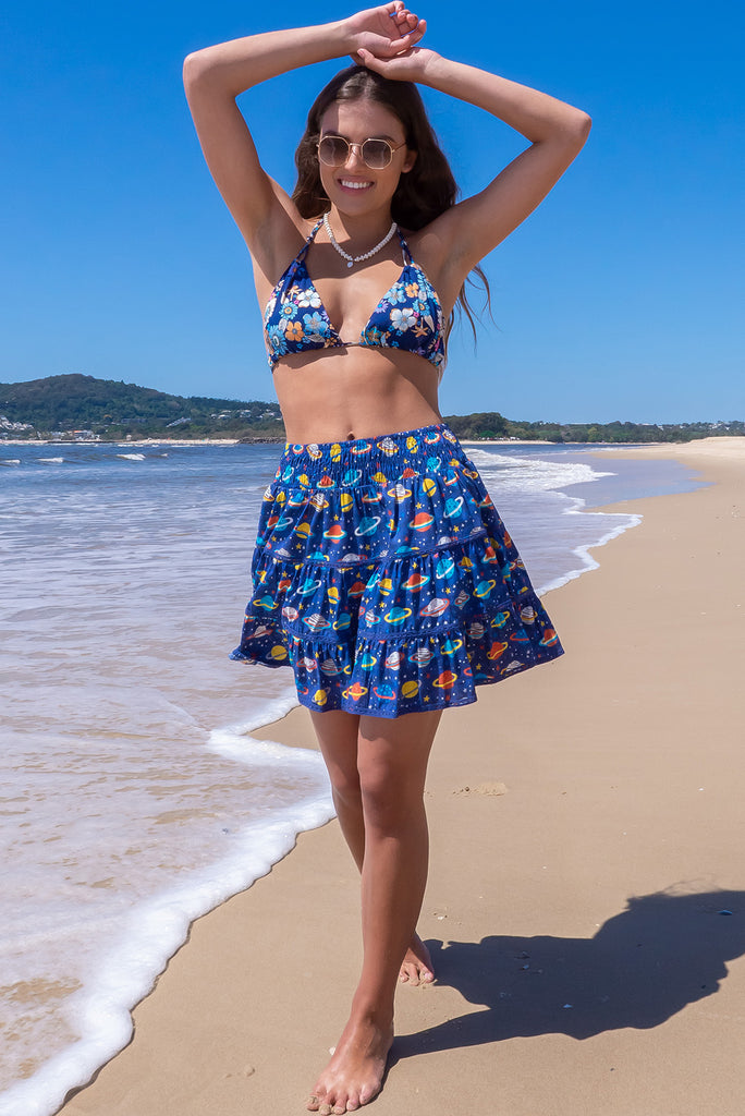 The Ziggy Cosmic Blue Mini Skirt is a retro-chic medium blue mini skirt with a planet print. The skirt features a shirred waistband, comfortable pull-on style, tiered, lace detailing and side pockets. This mini skirt is made from woven 100% cotton.