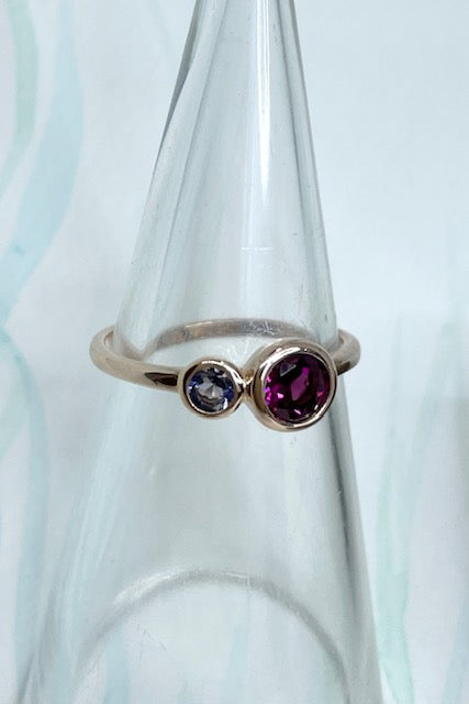 An unusual ring featuring a bright Rhodolite garnet and a smaller Iolite gemstone. Rose gold vermeil setting