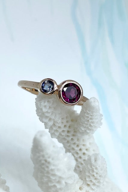 An unusual ring featuring a bright Rhodolite garnet and a smaller Iolite gemstone. Rose gold vermeil setting