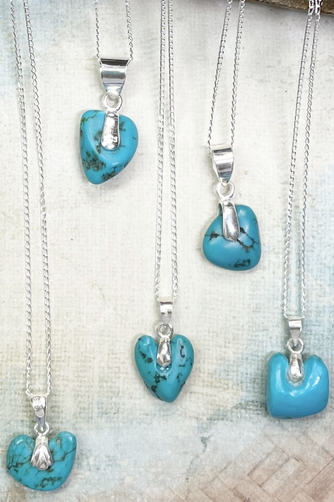 This lovely old turquoise pendant is a one off piece, hand carved into a rough heart shape and showing the mark of the artist who designed it. Set with a silver bail it hangs from a silver chain. 